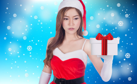 Christmas woman holding christmas gifts smiling. Cute beautiful Caucasian santa girl isolated on blue backgroundの写真素材