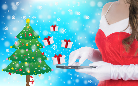 Christmas woman holding smart phone sent christmas gifts on winter background of blue color, christmas holiday conceptの写真素材