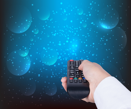 woman holding TV remote control on blue backgroundの写真素材