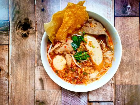Thai spicy soup noodle with pork, fish ball on wooden background.の写真素材