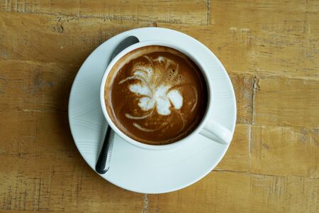 A cup of hot latte art coffee on wooden table