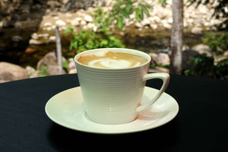 A cup of hot latte art coffee on wooden table
