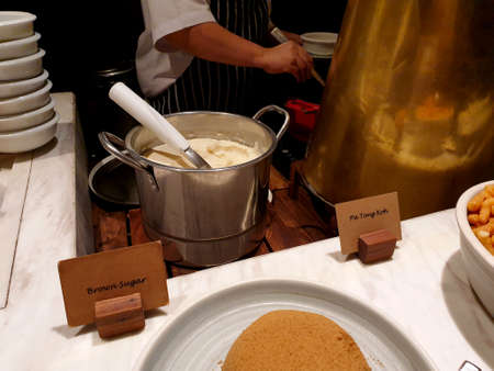 Chef of line buffet scoops up tofu pudding with ginger soup to the guest.