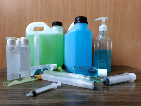Alcohol-based type of hand sanitizer gel in many types of packaging, syringes on wooden background, preferable to hand washing prevent against infection of Corona virus (Covid-19)の写真素材
