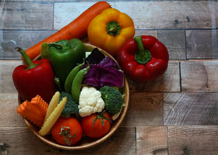Many type vegetable in the bowl on wooden background, such as red and yellow bell pepper, carrot,...