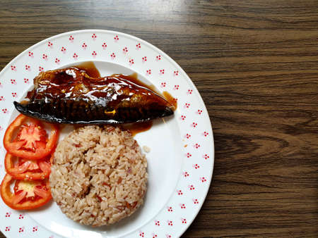 Saba fish grilled soy sauce with brown rice and fresh tomato on wooden background.
