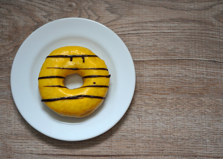 Yellow-colored sweet donuts on wooden background.の写真素材