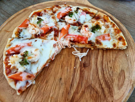 Delicious seafood cocktail pizza separated on the wooden plate.の写真素材