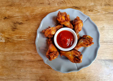 Fried Chicken Wings with tomato sauce on a wooden table.の写真素材