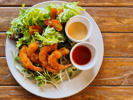 Fried shrimp salad with tartar sauce and tomato sauce on wooden background.の写真素材