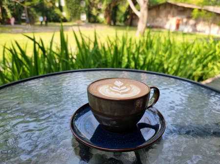 Sideway shop coffee, a cup of hot latte art coffee on the table.の写真素材