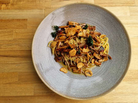 Stir fried spaghetti with dried chili and crispy bacon in a  plate on wooden background.の写真素材