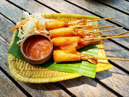 Crispy shrimp spring rolls with sweet sauce on a wooden table.の写真素材