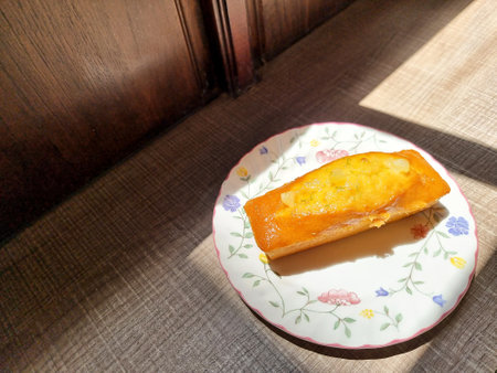 The lemon cake is on a ceramic plate with sun light from the window.の写真素材