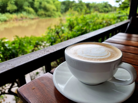 A cup of hot latte art simple tulip coffee on blurred the river backgroundの写真素材