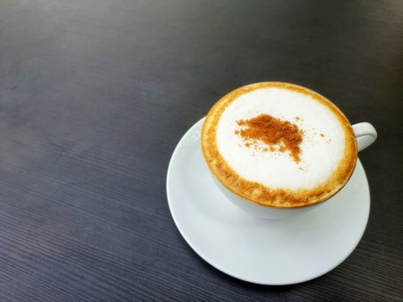 A cup of hot cappuccino coffee is on the table.