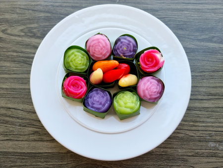 Top view traditional colorful sweet Thai desserts on a white plate, such as Deletable Imitation Fruits (Khanom Look Choup) and Khanom Alua Kularb or Rose shaped sweetmeatsの写真素材