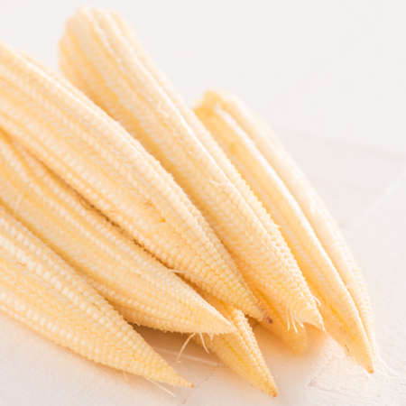 Baby corn on white wooden table,close up