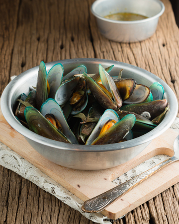 steam mussels with thai fresh herbs (basil, lemon grass, kaffir lime leaves) and seafood sauce on wooden backgroundの写真素材