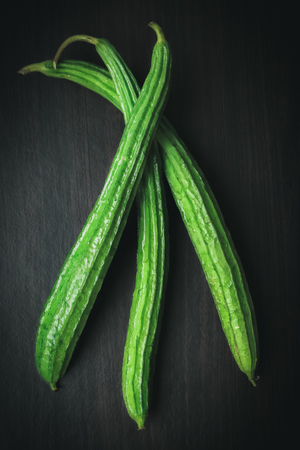 Angled Gourd or Angled Loofah Sponge gourd with Mystic Light on black wood backgroundの写真素材