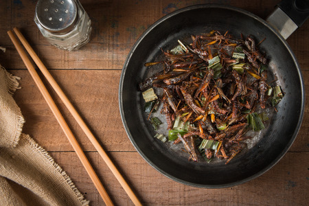 Fried grasshopper with pandan Season with salt, pepper and soy sauce. on old wooden tableの写真素材
