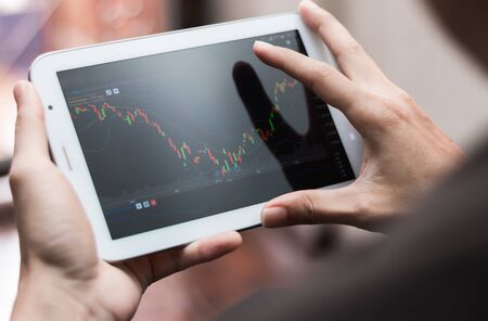 a man checking stock market on tablet, smartphone