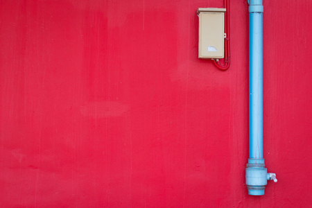 urban red wall texture with water pipe and electrical control box backgroundの写真素材