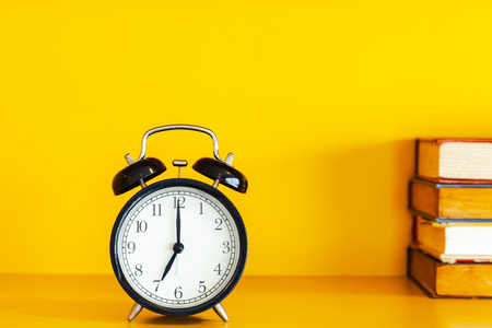 Alarm clock and book on yellow background with copy space.の写真素材