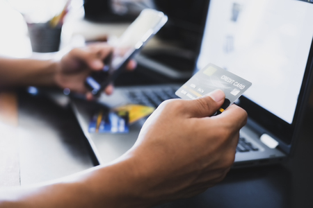 A man online shopping at home using credit card, Mobile phone and laptop for online shopping, technology and internet conceptの写真素材