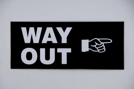 Vintage way out sign with a pointing hand attached to a white wallの写真素材