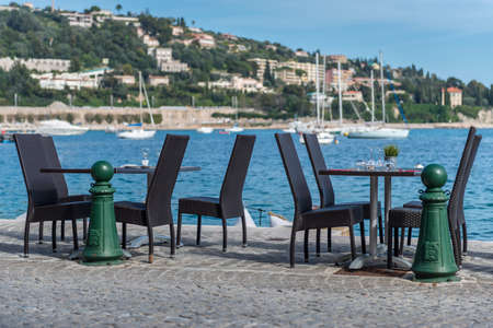 A pair of bistro tables on the harour edge with yachts in the backgroundの写真素材