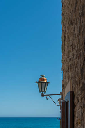 Traditional streetlight in Antibes old town with a view out to the azure blue Mediterranean seaの写真素材