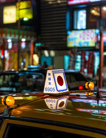 Closeup of a lit taxi sign on the roof of a yellow Japanese taxi on call at nightのeditorial素材