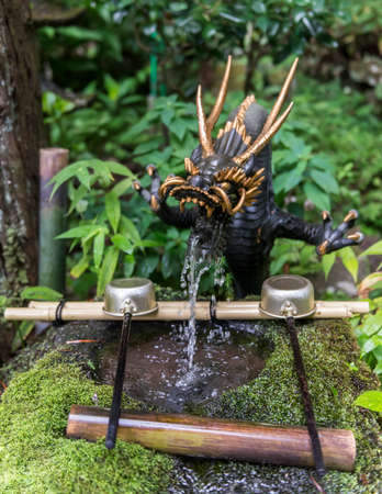 Dragon water fountain at a shrine with laddles for washing as a part of the ritual before entering the shrineの写真素材