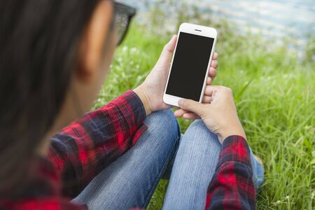 Female hands using smart phone with blank screen in the garden