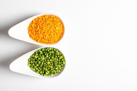 two types of legumes, beautifully arranged in cups and on a white background - green peas and orange...