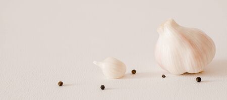 two young garlic with black peppercorns on a white background. Copy space. Close up. Long horizontal fileの写真素材