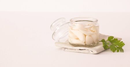 fermented garlic in a opend transparent jar on a textile on a white table. Decorated with cilantro. Copy spaseの写真素材