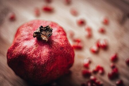 red pomegranate with sprinkled grains on a wooden backgroundの写真素材