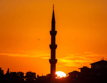 Dramatic sunset illuminates a historic mosque minaret in Istanbul creating a peaceful and spiritual atmosphere Ideal for travel and religious themes.の素材