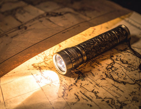 A vintage map is lit by a focused flashlight beam creating a sense of mystery and adventure Ideal for travel blogs or historical research.の素材