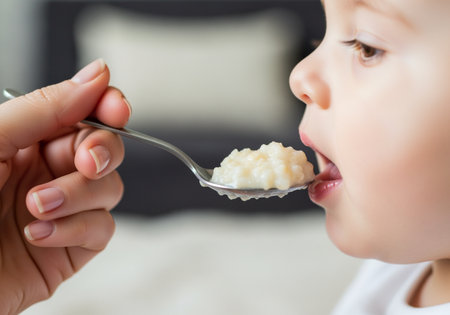 A caring adult feeds a young child with a spoon full of creamy food, creating a tender moment Perfect for illustrating parenting and nutrition.の素材