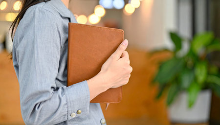 Business woman holding a notebook in the office, closeup of handsの素材