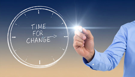 Mid section of businessman drawing time for change against blue background with vignetteの素材