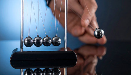 Close-up of Newton's cradle on blue background with reflection.の素材