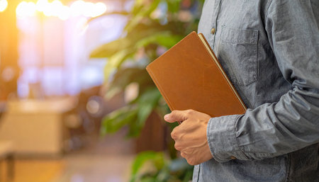 Man reading a book in a cafe. Close up of male hands holding a book.の素材