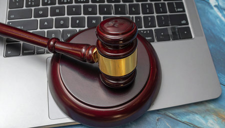Wooden judge gavel and laptop on blue wooden table, online justice conceptの素材