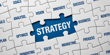 A jigsaw puzzle with a central piece labeled STRATEGY surrounded by other business-related words.の素材