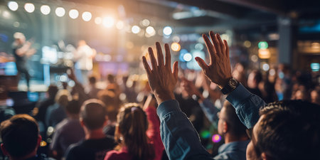 Crowd of people raising hands in front of stage lights during a concertの素材