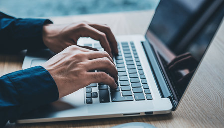 A close-up shot of hands actively typing on a laptop keyboard in a dimly lit environment.の素材